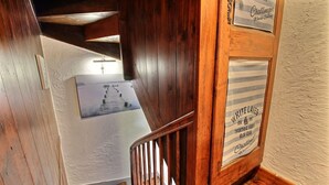 A wooden staircase with a white wall and a framed picture of a ship.
