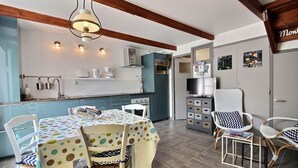 A kitchen with a central island, white chairs, and a dining table with a polka dot tablecloth.