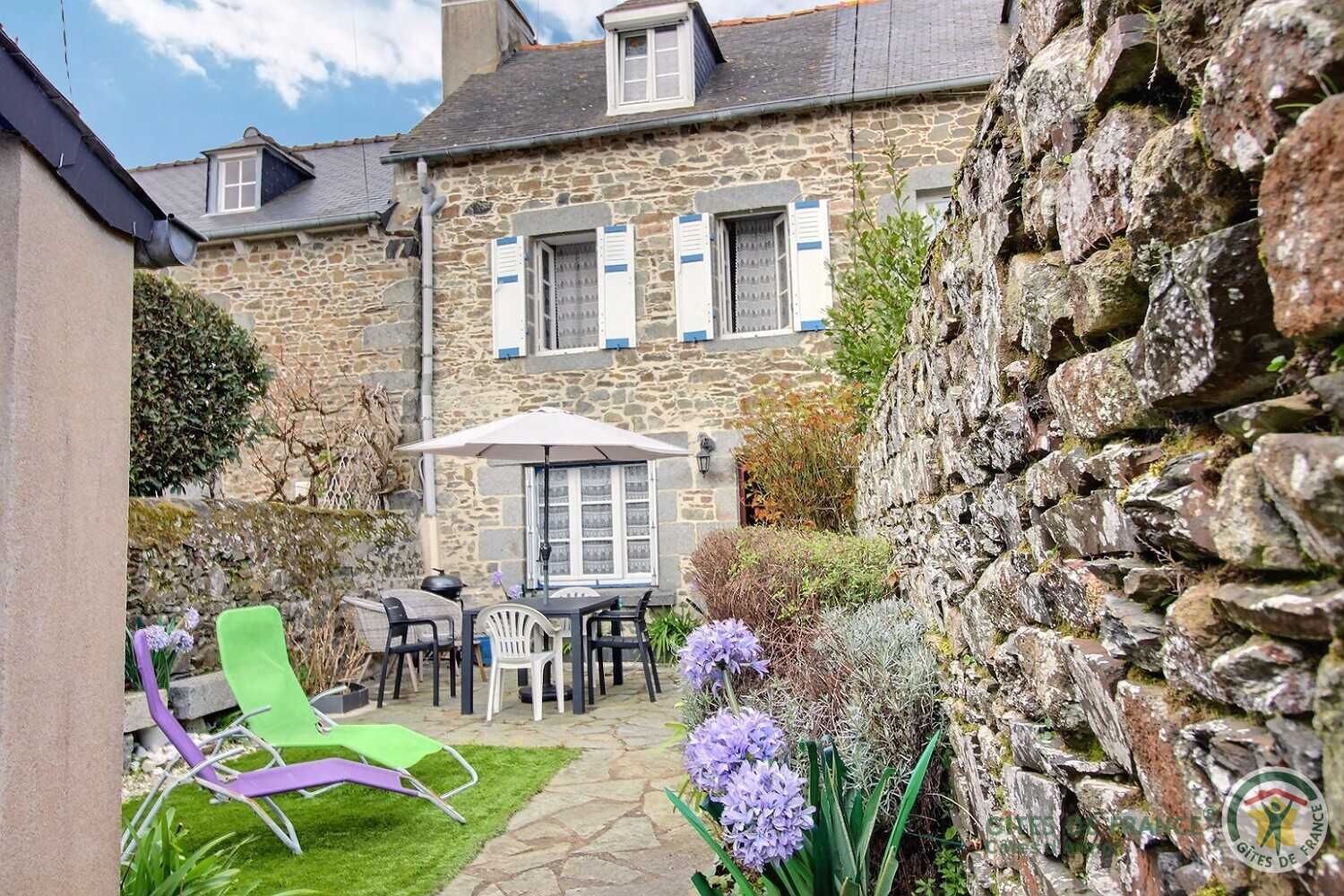 A stone building with a patio area featuring outdoor furniture and a table with an umbrella.