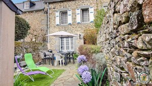 A stone building with a patio area featuring outdoor furniture and a table with an umbrella.