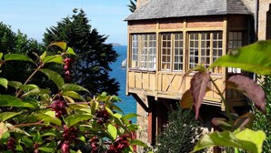 A wooden tower with large windows overlooking a body of water and a mountainous landscape. - Les Hortensias - ST Quay Perros (ST QUAY PERROS)