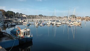 A marina with numerous boats docked, calm water, and a backdrop of residential buildings. - Les Hortensias - ST Quay Perros (ST QUAY PERROS)