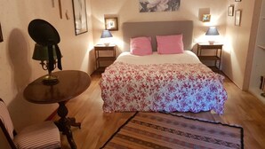 Une chambre à coucher avec un lit, deux lampes de chevet, une chaise, une table et un tapis à motifs.