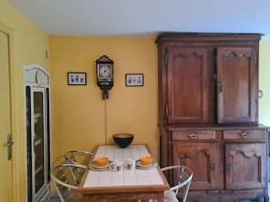 A dining area with a wooden table, chairs, a clock, and a cabinet.