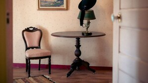 Une pièce avec une table ronde, une chaise, une lampe et un tableau encadré accroché au mur.