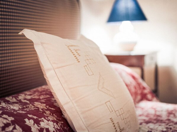 A pillow with a geometric pattern on a bed with a floral bedspread.
