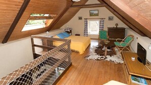 Un dormitorio acogedor en el ático con techo de madera, una cama, un escritorio y una silla.