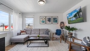 A modern living room with a sectional sofa, a coffee table, a TV, and framed pictures on the wall.