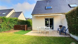 Une maison dotée d’un patio comprenant une table et des chaises, une porte-fenêtre coulissante et une petite fenêtre.