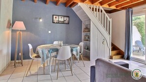 Un espace repas comprenant une table ronde, des chaises, une lampe et un escalier menant à un niveau supérieur.