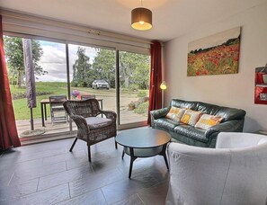 A modern living room with a leather sofa, a wicker chair, and a round table.