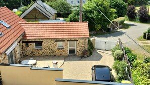 Ein Haus aus Stein mit rotem Ziegeldach, einem kleinen Vorgarten und einem parkenden Auto.