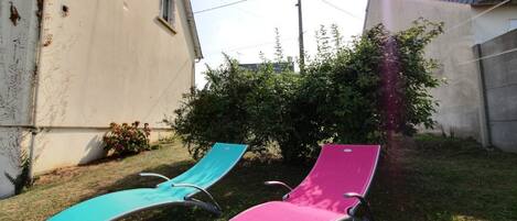 Zwei Liegestühle in einem Garten mit einem Haus im Hintergrund.