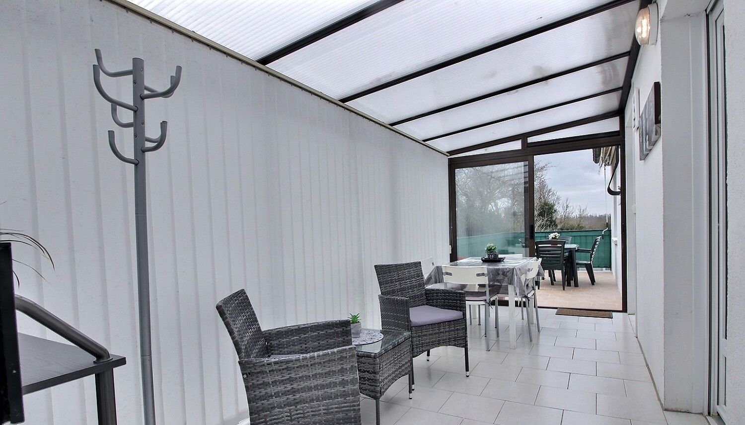 A covered patio area with wicker furniture, a table, and a chair.