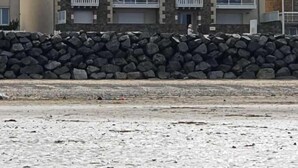 Un edificio de varios pisos con fachada de piedra, balcones y techo plano.