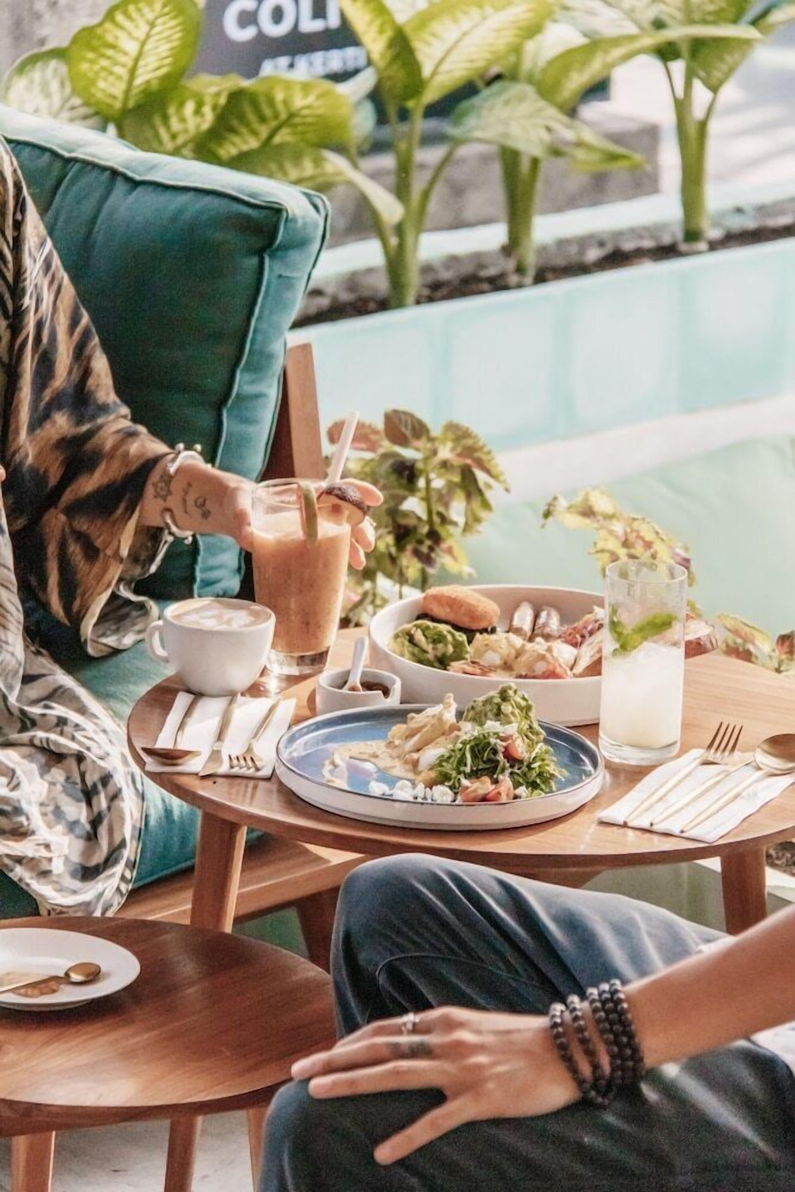Une table à manger avec une salade, une boisson et une tasse de café.