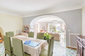 Ein Essbereich mit Tisch für vier Personen, umgeben von Stühlen, und Blick auf einen Balkon mit einer Couch.