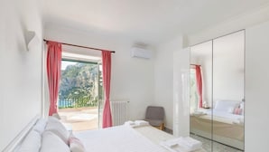 Une chambre d’hôtel avec un lit, une chaise, un grand miroir et une vue sur l’extérieur.