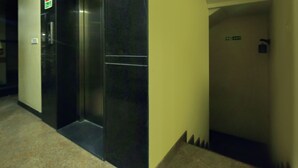 A hallway with a black elevator and a door with a sign. - Treebo Trend Hotel Sampradaya (Bengaluru)