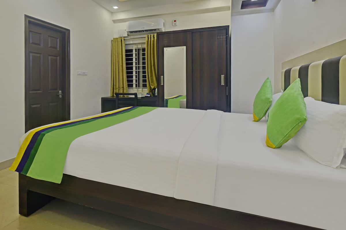 A neatly made bed with a green and yellow striped bedspread, a wooden headboard, and two green pillows.