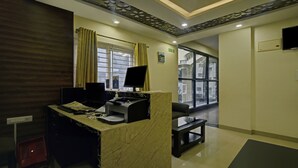 A reception area with a marble counter, computer monitors, and a large window with curtains. - Treebo Trend Hotel Sampradaya (Bengaluru)