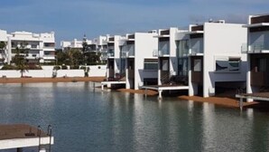 A modern hotel with multiple white buildings, a pool, and a clear sky.