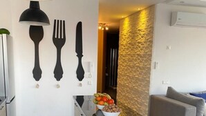 A modern kitchen with a central island, black stools, and a dining area with a sofa. - APPT AT EDEN ISLAND BOUZNIKA WATERFRONT RESIDENCE (Bouznika)