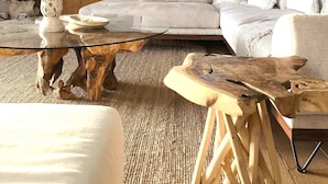 A modern living room with a large sectional sofa, a glass coffee table with a wooden base, a side table, and a large mirror above the sofa. - Sea View Luxury Villa (Siviri)