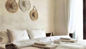 A neatly made bed with a patterned throw blanket, white pillows, and three woven wall hangings. - Sea View Luxury Villa (Siviri)