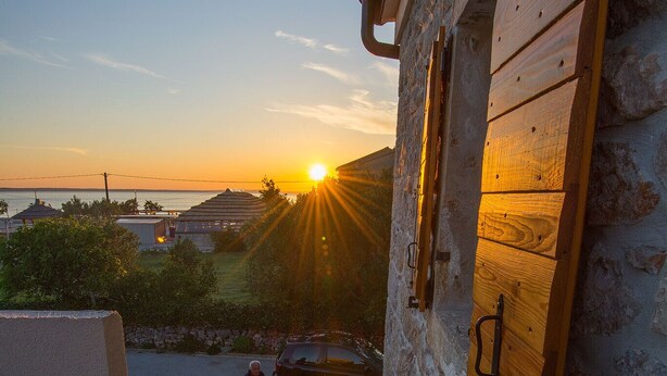 A stone building with a wooden staircase leading to a balcony overlooking a sunset. - Steinhaus Punta Fuer 10 Personen-im Ortszentrum (Starigrad Paklenica)