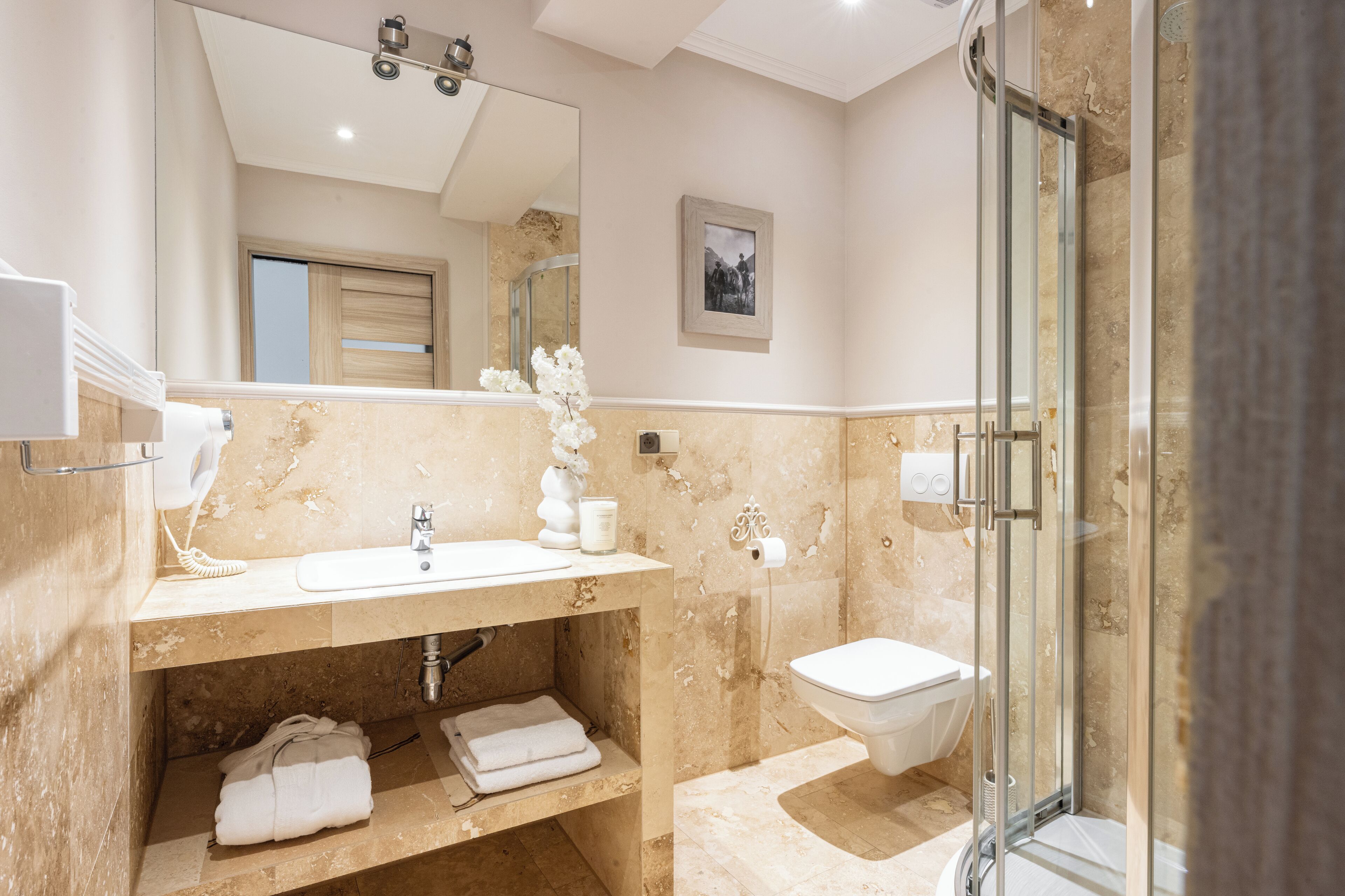 Une salle de bain avec un lavabo en marbre, une douche en verre et des toilettes.