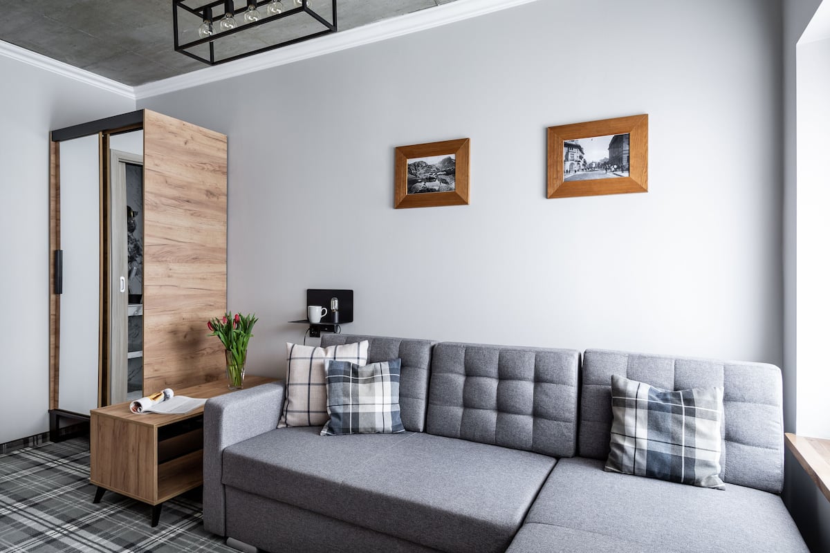 A modern living room with a grey sofa, wooden sideboard, and two framed photographs on the wall.