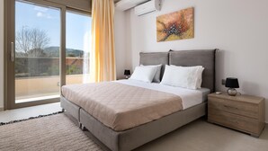 A bedroom with a bed, bedside tables, a window with curtains, and a painting on the wall. - Panthea Villa in Ialysos (Ιαλυσός)