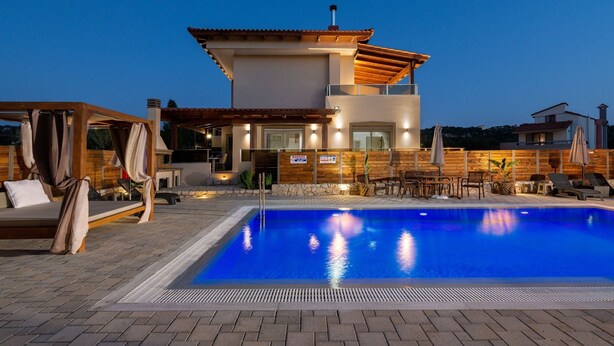 A modern two-story house with a swimming pool, outdoor seating, and a wooden fence. - Panthea Villa in Ialysos (Ιαλυσός)