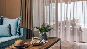 A modern living room with a blue sofa, a wooden coffee table, a woven hat, a decorative shell, and a potted plant. - Terra Lucis Mountain Residences/ Mare Villa (Zakynthos)