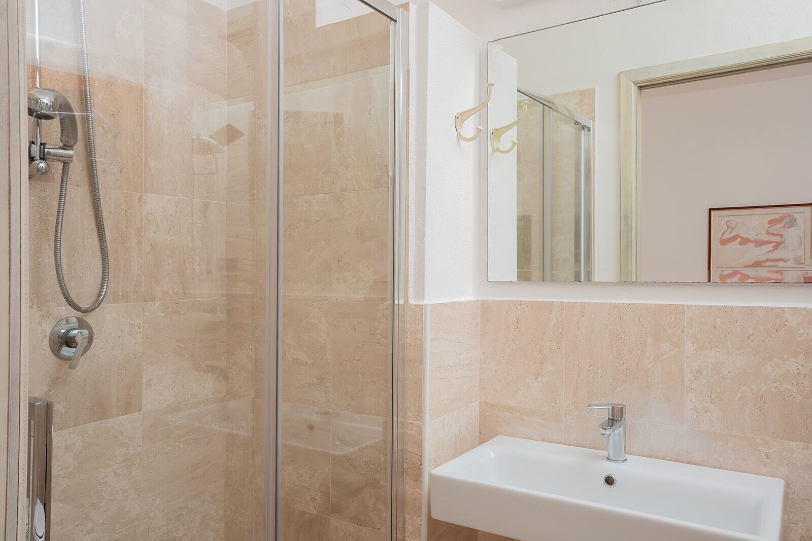 A modern bathroom with a glass-enclosed shower, a white sink, and a mirror above the sink.
