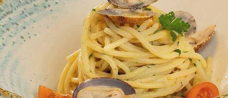 A bowl of spaghetti with clams and garnished with parsley.