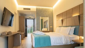Een moderne hotelkamer met een groot bed, een aan de muur bevestigde televisie en een badkamer zichtbaar door een glazen deur.
