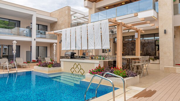 Een modern zwembadgedeelte met een bar, ligbedden en een glazen balustrade.
