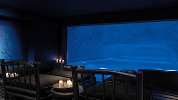 Relax in a serene space with a large screen, comfortable seating, and warm candlelight.