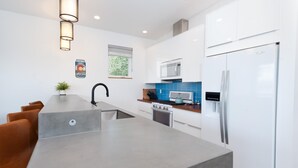 Une cuisine moderne dotée d’un îlot central, d’appareils électroménagers en acier inoxydable et d’un revêtement mural bleu.