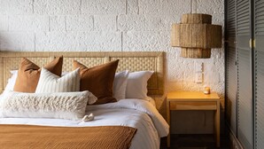 A bedroom with a bed, nightstand, lamp, and a textured wall. - HOLT's Villa Noria, La Casa del Barro Verde (Oaxaca de Juárez)