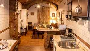 A cozy kitchen with a stone arch, a dining area with a sofa, and a bar area with stools. - Los Gaitanes Rural House (Valverde de Leganés)