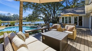 Une terrasse en bois avec des meubles d’extérieur, une piscine et une vue sur un lac.