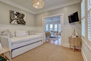 A modern bedroom with a white sofa, a flat-screen TV, and a large window. - 8 Channel Ave A - Perfect location with sound front views. Sleeps 10. (Wrightsville Beach)