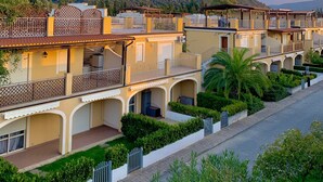 A row of Mediterranean-style buildings with balconies, a paved walkway, and lush greenery. - Anna's HOUSE - Solarium Terrace (Pizzo)