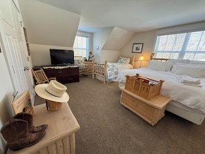 A bedroom with a bed, a TV, a dresser, a hat, and a wooden chest. - A River Runs Through It-10 private acres on the Black River, South Haven (Pullman)
