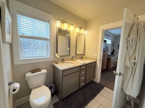 A bathroom with a toilet, two sinks, a vanity with drawers, a mirror, and a window with blinds. - A River Runs Through It-10 private acres on the Black River, South Haven (Pullman)