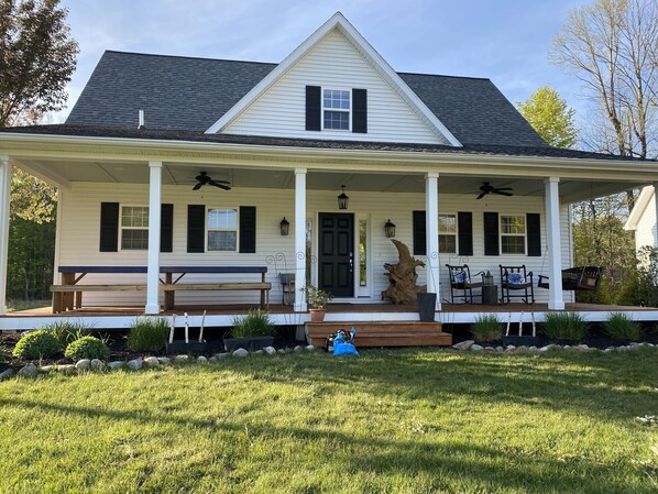 A two-story house with a porch, a front door, and a large tree trunk decoration. - A River Runs Through It-10 private acres on the Black River, South Haven (Pullman)