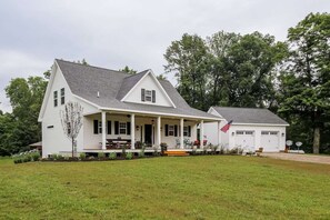 A white two-story house with a front porch, a garage, and an American flag. - A River Runs Through It-10 private acres on the Black River, South Haven (Pullman)